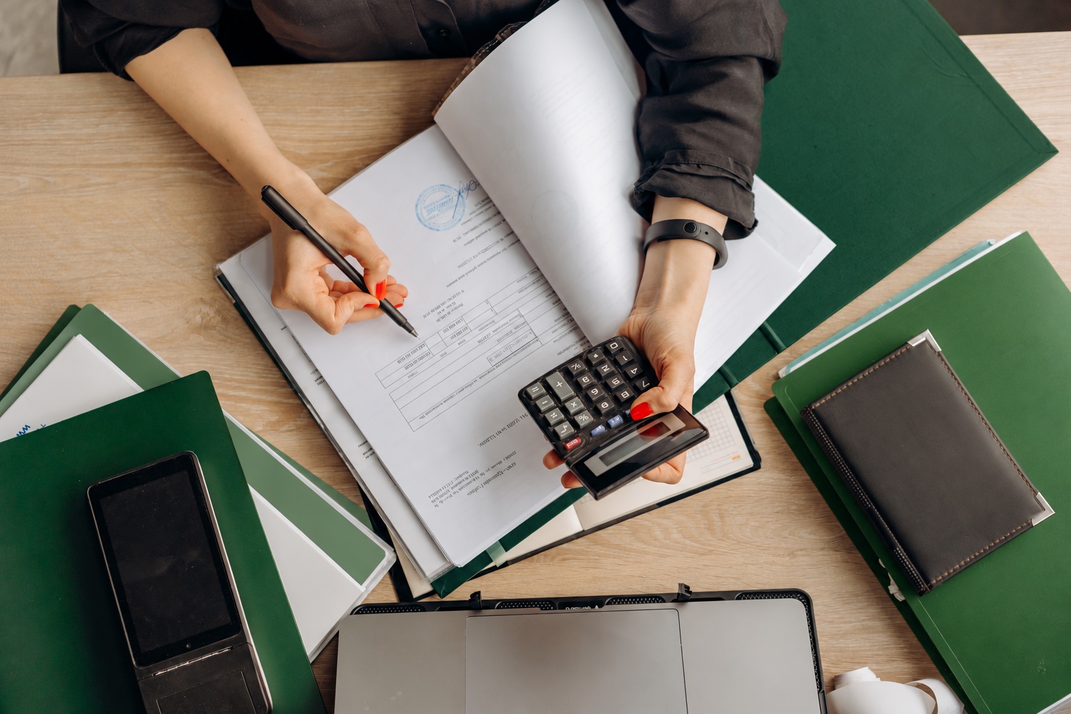 Reviewing financial paperwork with a calculator and green folders